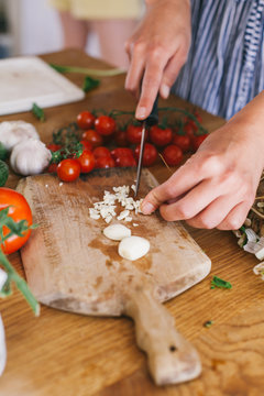 Female hands cutting garlic on a wooden rustic board