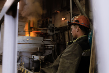 Young worker resting near furnace