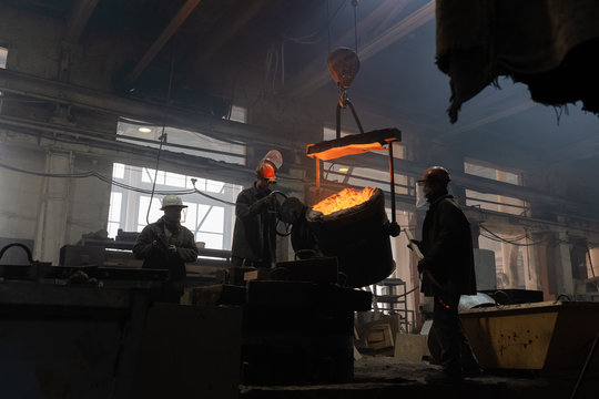 Men casting metal in grungy workshop