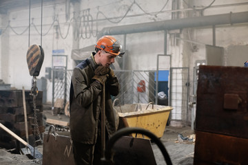 Male apprentice with shovel in factory workshop