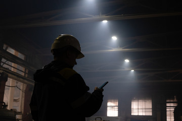 Unrecognizable factory worker using smartphone in workshop