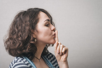 Beautiful woman with secret  finger over lips.