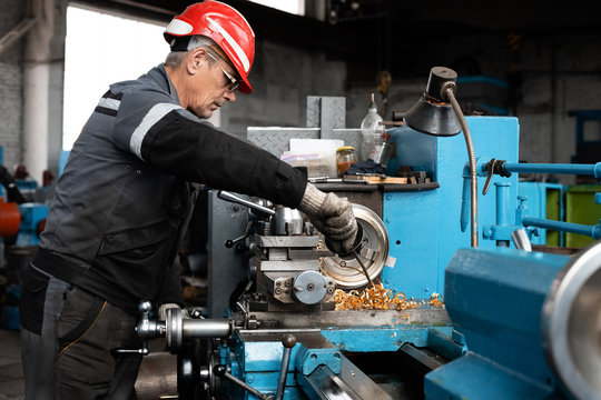 Elderly worker removing shavings from lathe