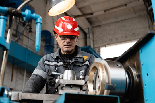 Elderly man near turning lathe in factory - Powered by Adobe