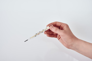 Female hand holding a thermometer that shows 39.6 Celsius against white background 