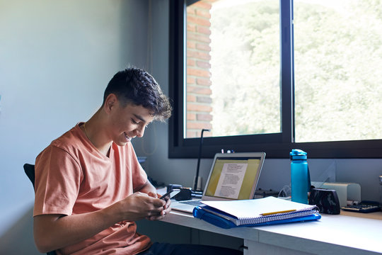 Teenager using mobile phone while studying