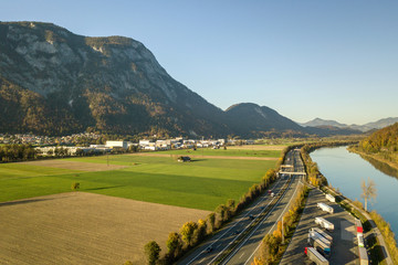 Aerial view of highway interstate road with fast moving traffic near big river in Alps mountains