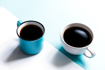 Flatlay top view of two coffee cups on white and blue paper background. Selective focus