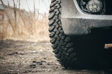Car mud terrain wheel on dirt road background.