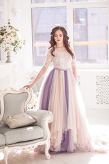 Fototapeta premium Bride in color wedding dress. Beautiful model in a beautiful wedding dress in a white photo studio. Portrait of an attractive girl in a beautiful interior.