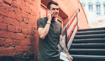 Young male talking to friend on mobile in street