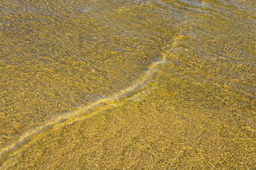 Sandy bottom of a river shot on a sunny spring day. Background for clear water.
