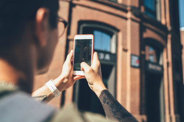 Resting man making photo while having excursion at city street