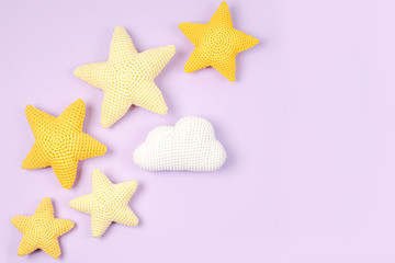 Knitted toy yellow stars on purple background. Baby stuff and accessories. Flat lay, top view