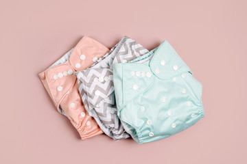 Reusable cloth baby diapers. Eco friendly cloth nappies on a pink background. Sustainable...