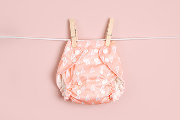 Reusable cloth baby diapers drying on a clothes  line. Eco friendly cloth nappies on a pink...