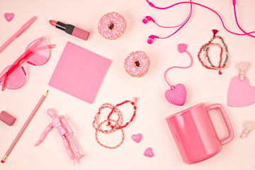 Flat lay with pink accessories, tea cup and donuts over light pink background. Top view. Morning rituals, stay at home idea