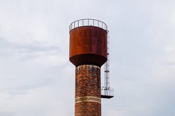 Rusty water tower against sky. Old water pump.