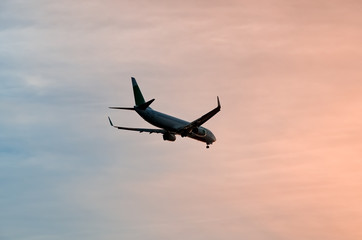 Large plane flies in the evening sunset sky, dramatic painted sky and airplane silhouette with...