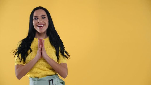Beautiful tricky girl smiling at camera isolated on yellow
