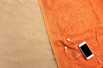 Beach towel, headphones, on sand background. Minimal beach concept .Top view with copy space.