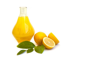 Lemon juice in a glass jug, lemons on an empty white background.