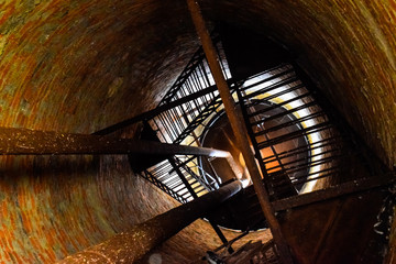 Fototapeta na wymiar Rusty water tower inside view from top to bottom. Old water pump. Ladder to water tank, pigeon droppings.