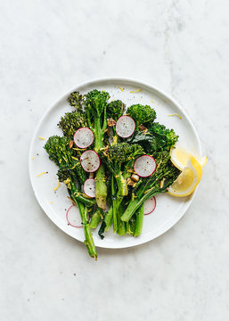 Plate of stir-fried broccolini with slice radish and lemon zest