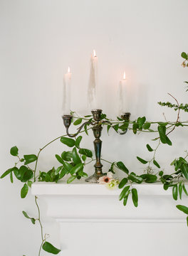 taper candles on candelabra with vines on fireplace mantle