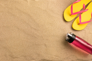 Fototapeta na wymiar Top view flip flops and water bottle with copy space. Traveler accessories on sand. Travel vacation concept. Summer background. Border composition made of towel