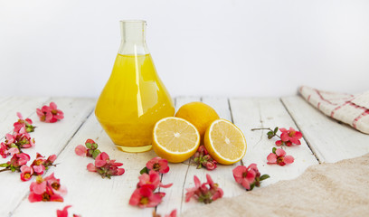 Lemon juice in a glass jug, lemons on an empty white background.