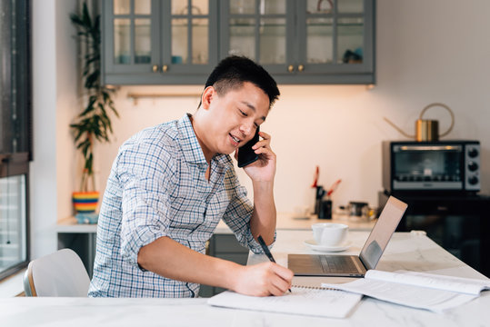 Young asian man working at home while using cell phone