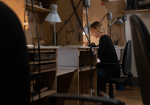 Female goldsmith sitting at workbench amidst tools