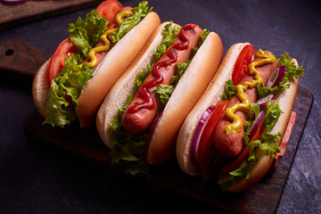 Hot dog with pickles and lettuce on blue concrete background.