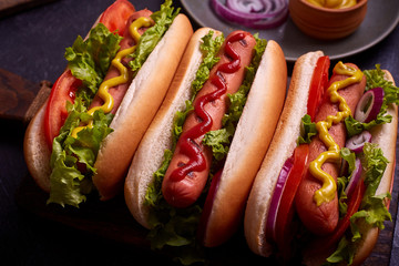 Hot dog with pickles and lettuce on blue concrete background.