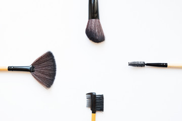 four makeup brushes on a white background, top view.
