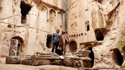 Travel couple alone at ancient Gumusler Monastery surrounded by old stones and ruins in Gumusler,...