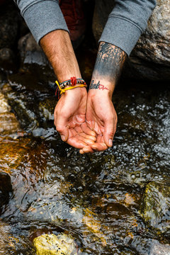 Mand hands about to scoop water from river