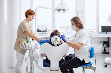 Man dentist and dental assistant at work in surgery, annual check-up.