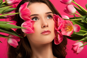 Obraz na płótnie Canvas beautiful girl with spring tulip flowers isolated on pink