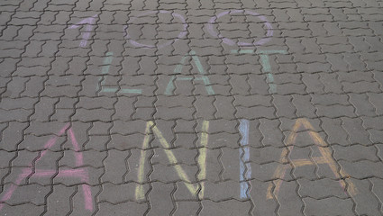 Napis zrobiony kredą na chodniku, w tłumaczeniu napis oznacza 