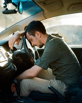 Bored, tired man sleeping at the wheel of his car