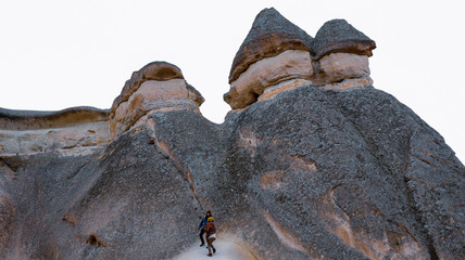 Travel couple walking around rock formations in Pasabag Valley, the valley of the monks in Cappadocia, Happy couple standing near cave houses surrounded by fairy chimneys at Pasabag Valley in Turkey
