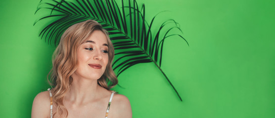 Girl with a palm date leaf Phoenix roebeleni on a green background