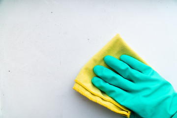 hand in green rubber glove wipes dusty table with a rag