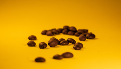 Arabica coffee beans, lying on the yellow gradient texture table