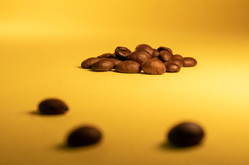 Arabica coffee beans, lying on the yellow gradient texture table