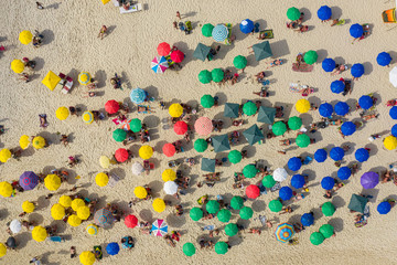 Drone shot of beach goers under umbrellas on the beach