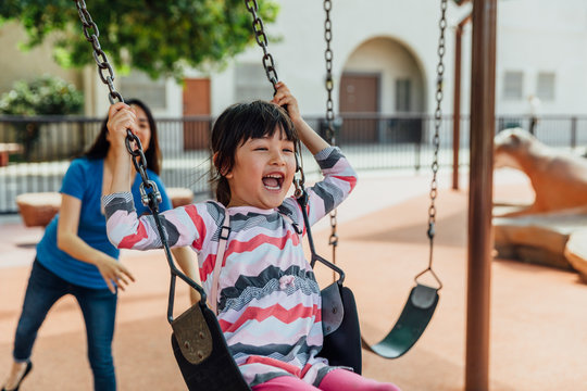 Asian Child Pushed On The Swing