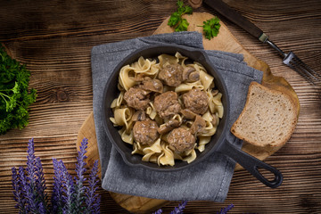 Pork meatballs with noodles in a cast iron skillet.